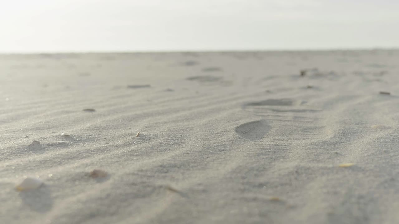 Footsteps on a white sand beach at dawn.