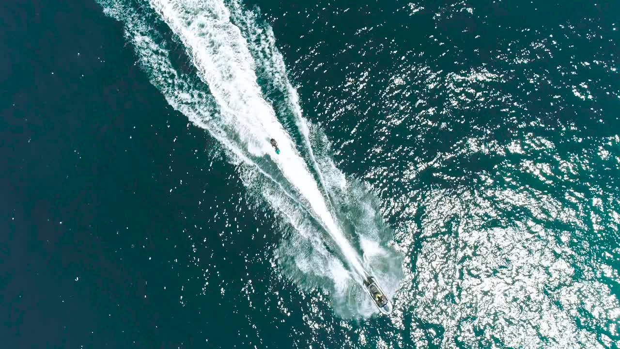 Jet Ski and surf rider on jet skiing on tropical blue and green sea waterscape. Top down aerial footage of sport activity with ocean waves ripple. beautiful high adrenaline and extreme sports scene.