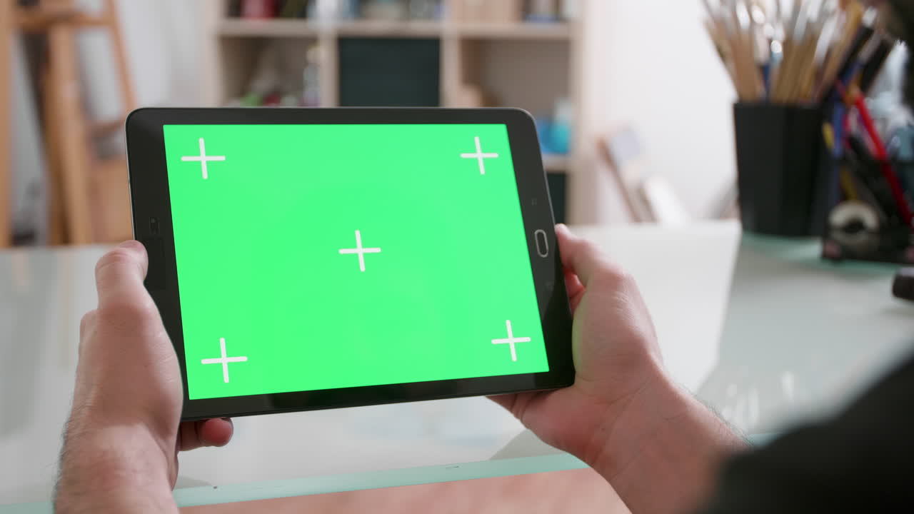 녹색 화면 을 가진 태블릿 을 들고 있는 사람