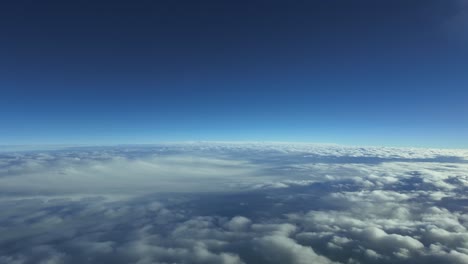 pov flying at supersonic speed over a layer of stratus clouds with a deep blue sky