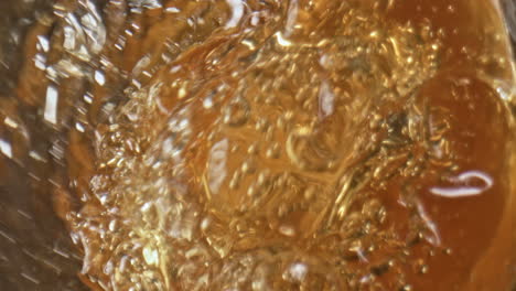 golden ale jet inside glassware closeup. barley liquid splashing pouring glass