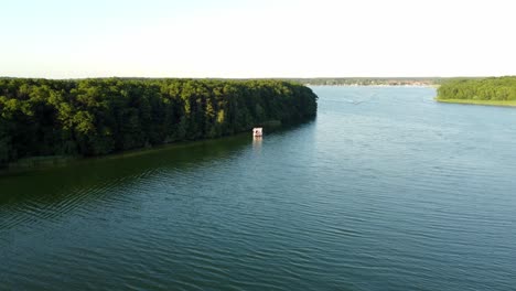 House-boat-floating-on-a-large-natural-lake-next-to-a-forest-in-Brandenburg,-Germany