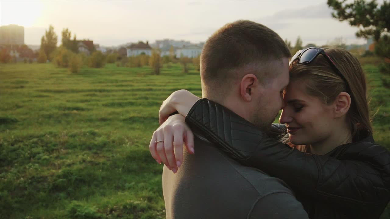 una pareja abrazándose en un parque al atardecer