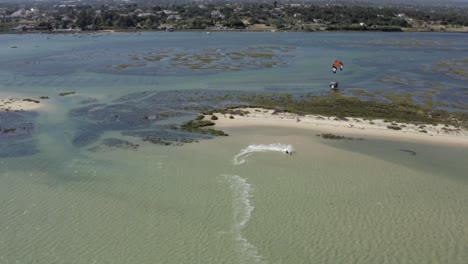 Epischer-Schuss-Eines-Kite-windsurfers,-Der-Ruhiges-Tropisches-Wasser-Von-Fuzeta-Zerschneidet,-Portugal-drohnenantenne