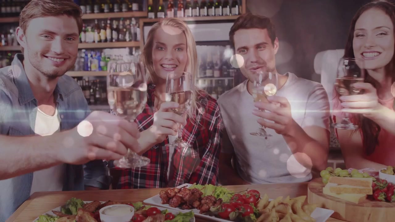 Cuatro amigos revisando el teléfono y luego chocando copas de vino en un bar, celebrando con una superposición de destellos