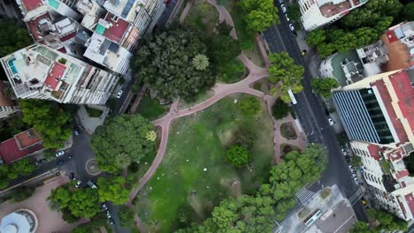 Orbital-rising-over-Barrancas-de-Belgrano-park-surrounded-by-buildings-in-busy-Buenos-Aires-neighborhood,-Argentina