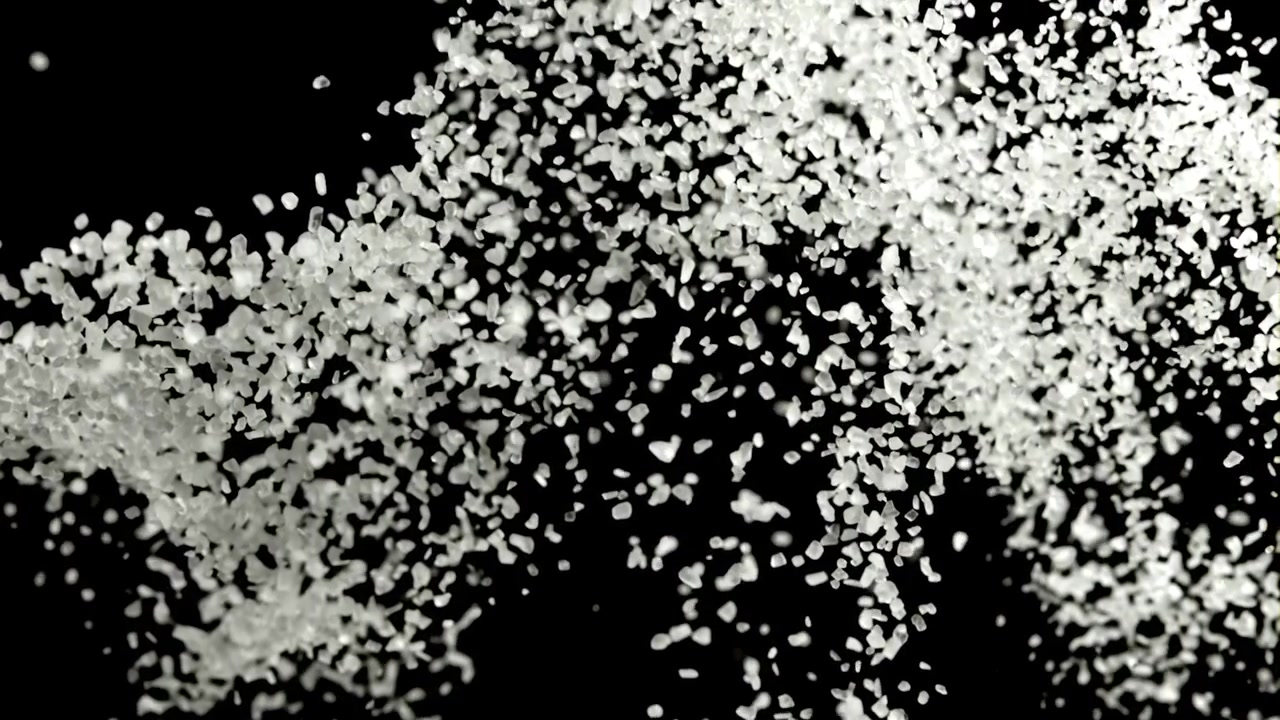Particelle granulari bianche che cadono e si diffondono su sfondo nero