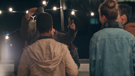 multi-ethnic-group-of-friends-having-fun-dancing-to-music-on-rooftop-at-night-enjoying-celebration-party