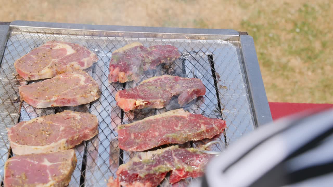 diferentes tipos de carne siendo a la parrilla en la parte superior de una barbacoa