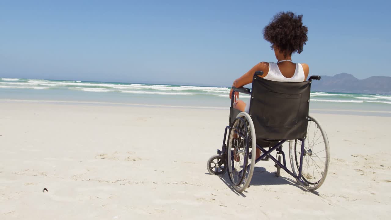Disabled woman sitting on wheelchair at beach 4k