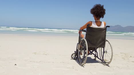 mujer discapacitada sentada en silla de ruedas en la playa 4k