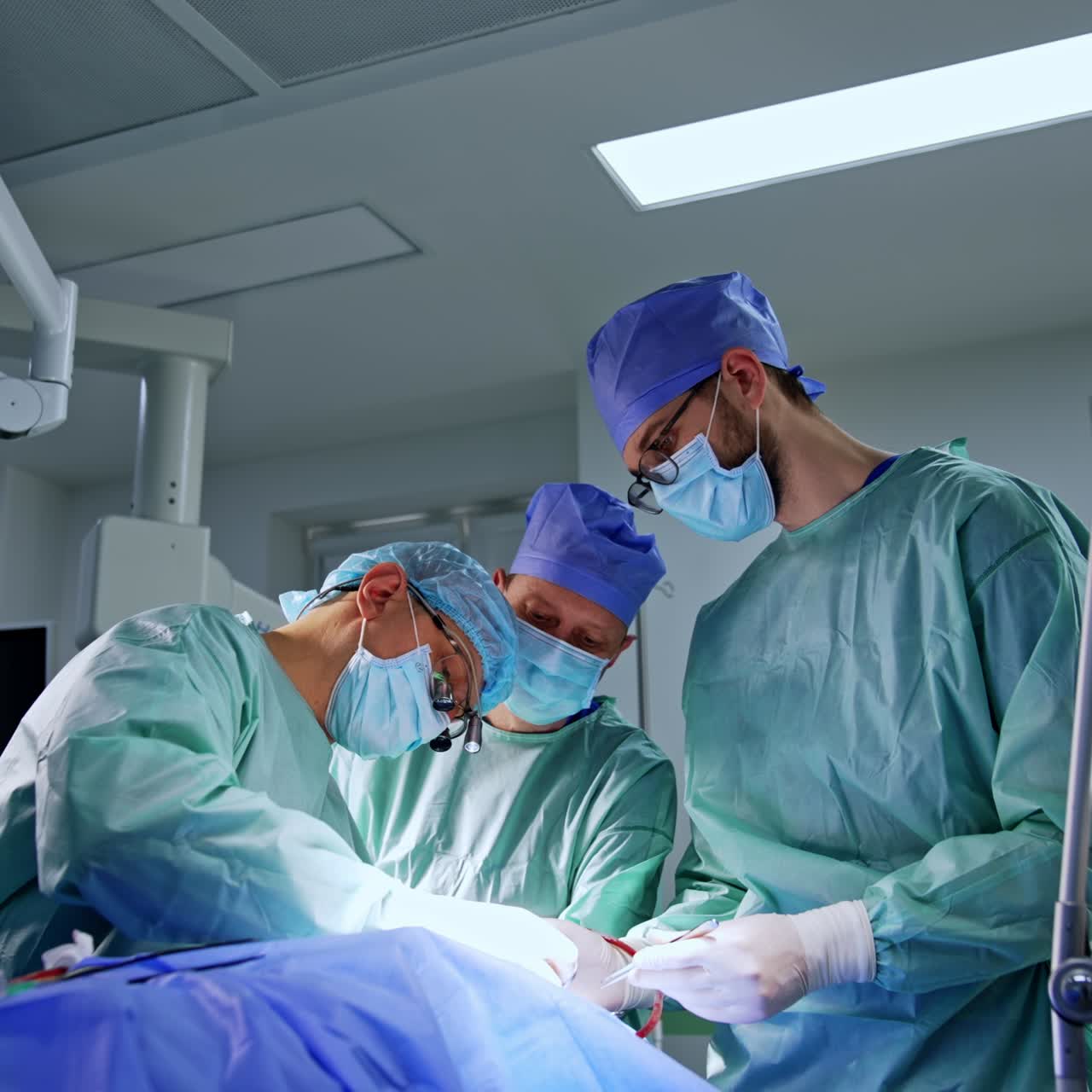 Three doctors stand at the patient's head. Neurosurgery professionals perform procedure on brain