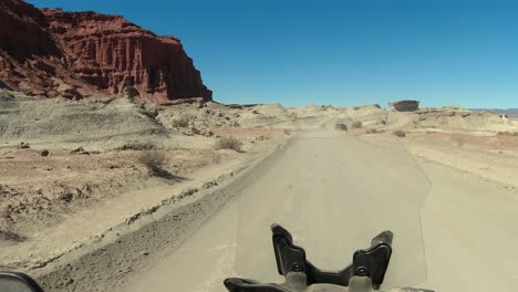 Motorcycle-POV:-Rider-follows-vehicle-on-badlands-canyon-dirt-road