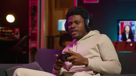 african american guy in modern apartment plays video games competition, relaxing and having fun. person in multiplayer game on gaming console during leisure time at home. camera a.