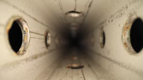 pulling out of a zinc-plated steel perforated square tube with a wide angle macro probe lens - showing texture on metal and some spots of surface rust on the holes