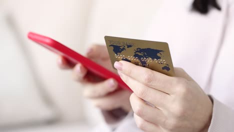 in female hand is smartphone and bank credit card closeup