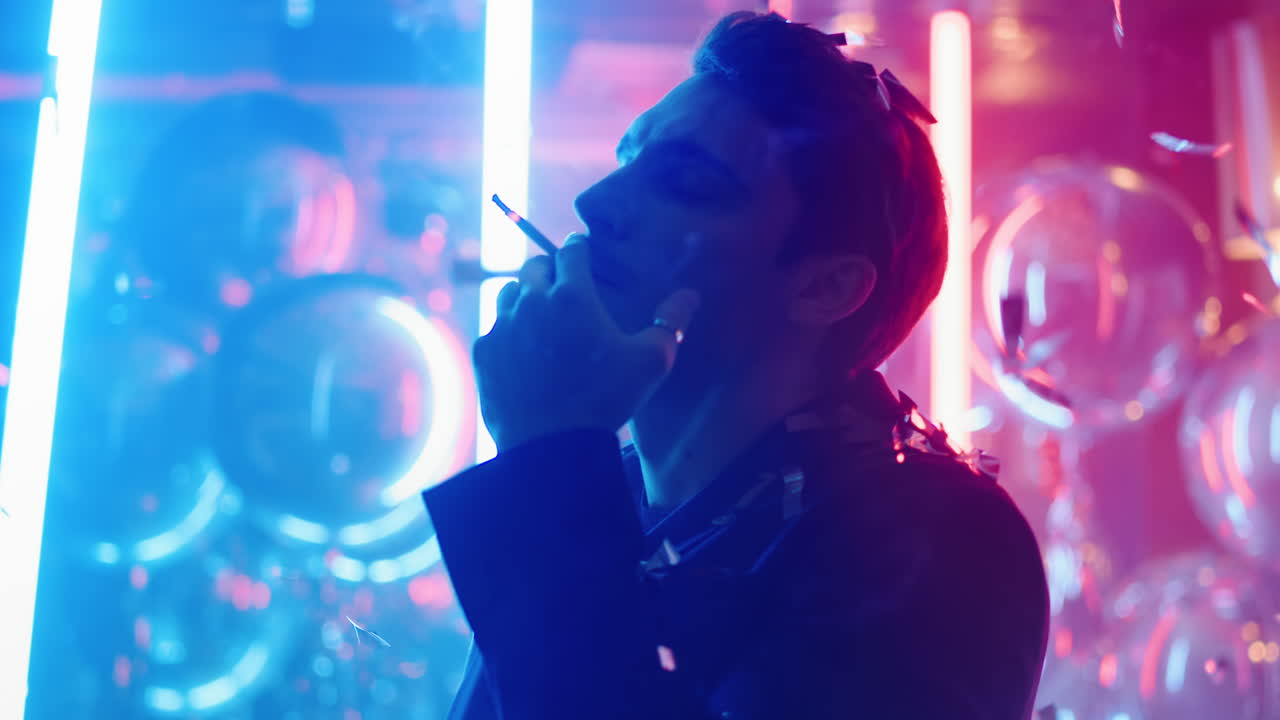 hombre relajado bailando con un cigarrillo bajo confeti. hombre sexy fumando en una fiesta
