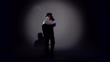 a man in a suit and fedora under a spotlight