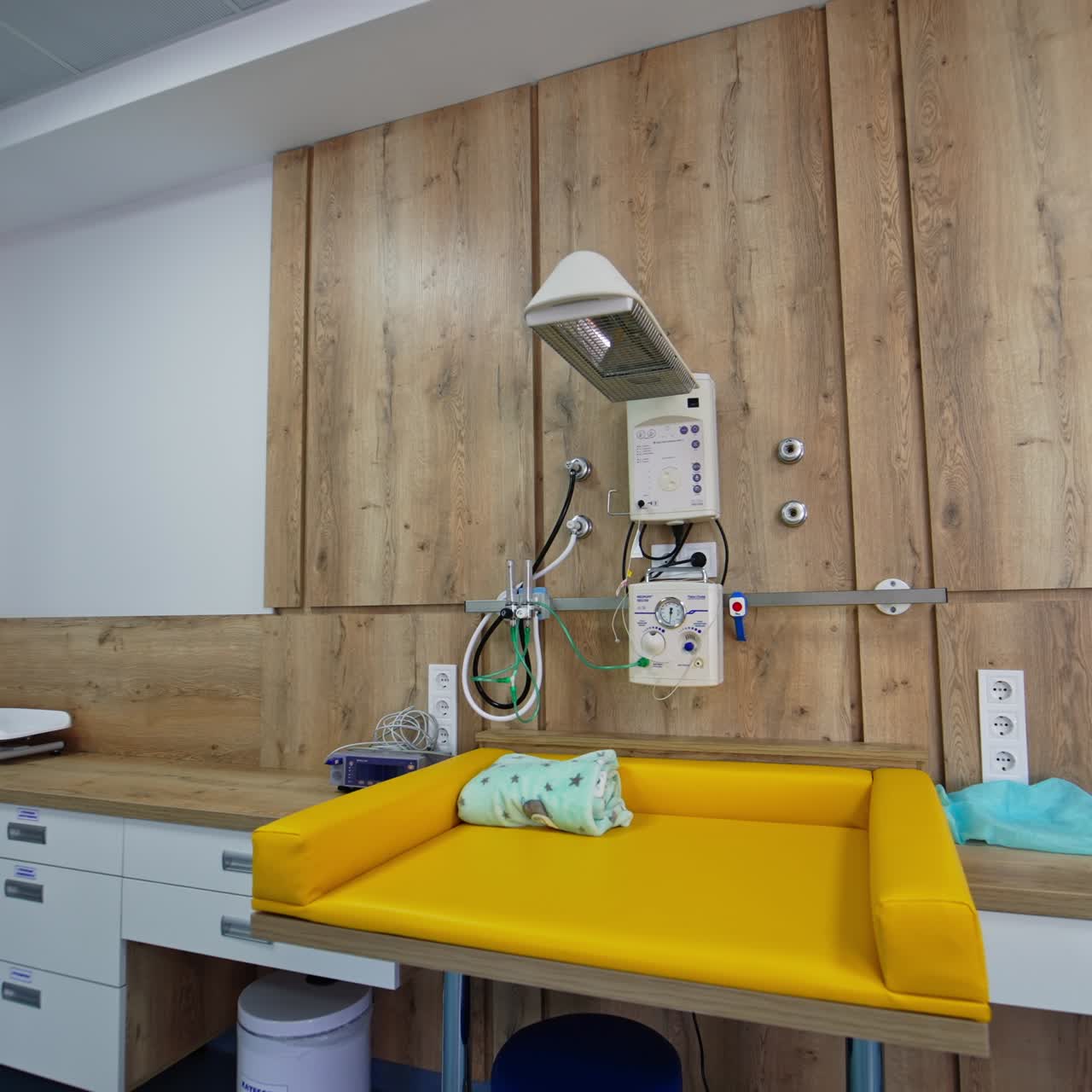 Mesa amarilla suave para limpiar a los recién nacidos. Innovador equipo acoplado sobre la mesa para el cuidado de los recién nacidos.
