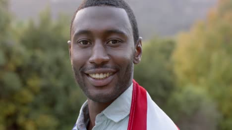 portrait of african american man holding flag of usa in garden, slow motion