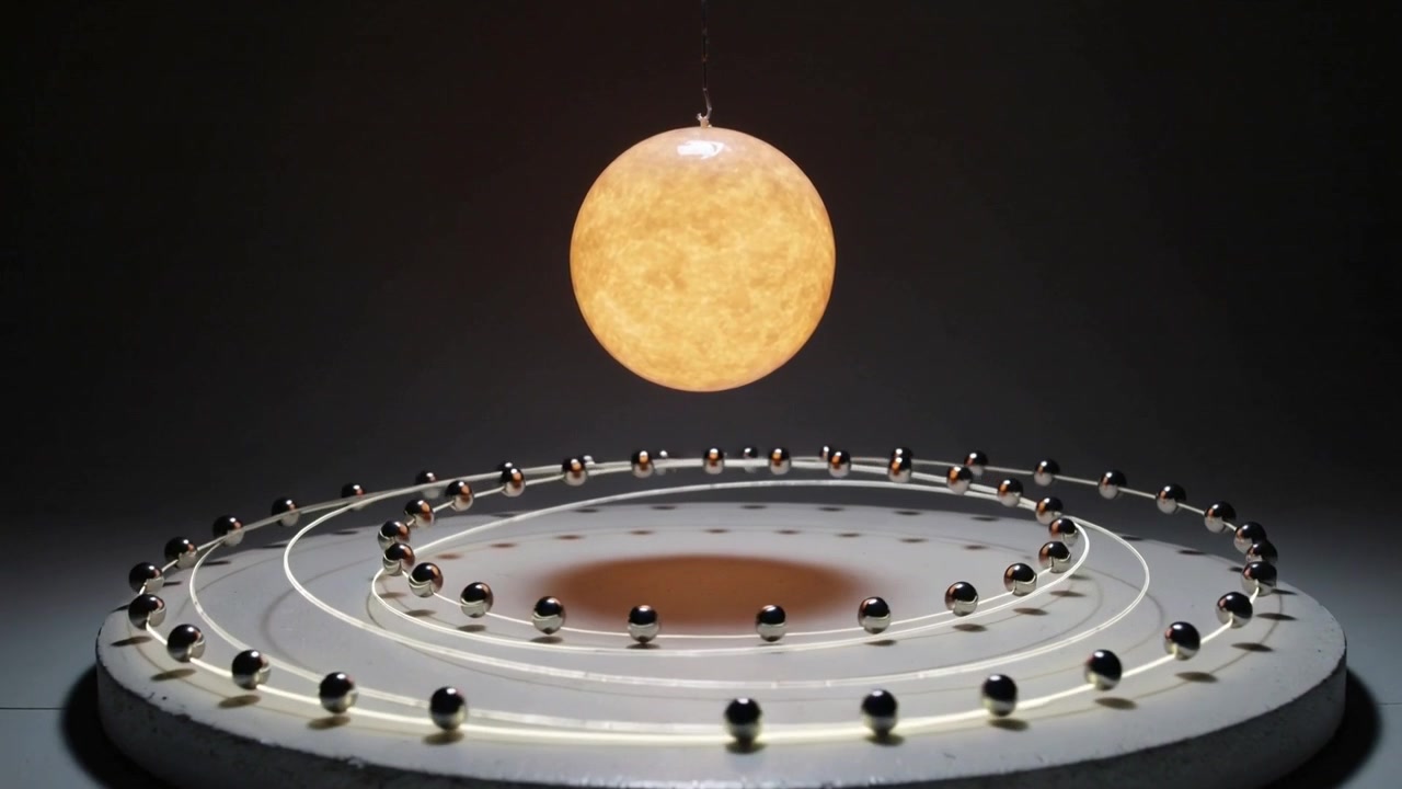 Drive engaging tabletop demo moving steel marbles clockwise on three tracks under lamp for display
