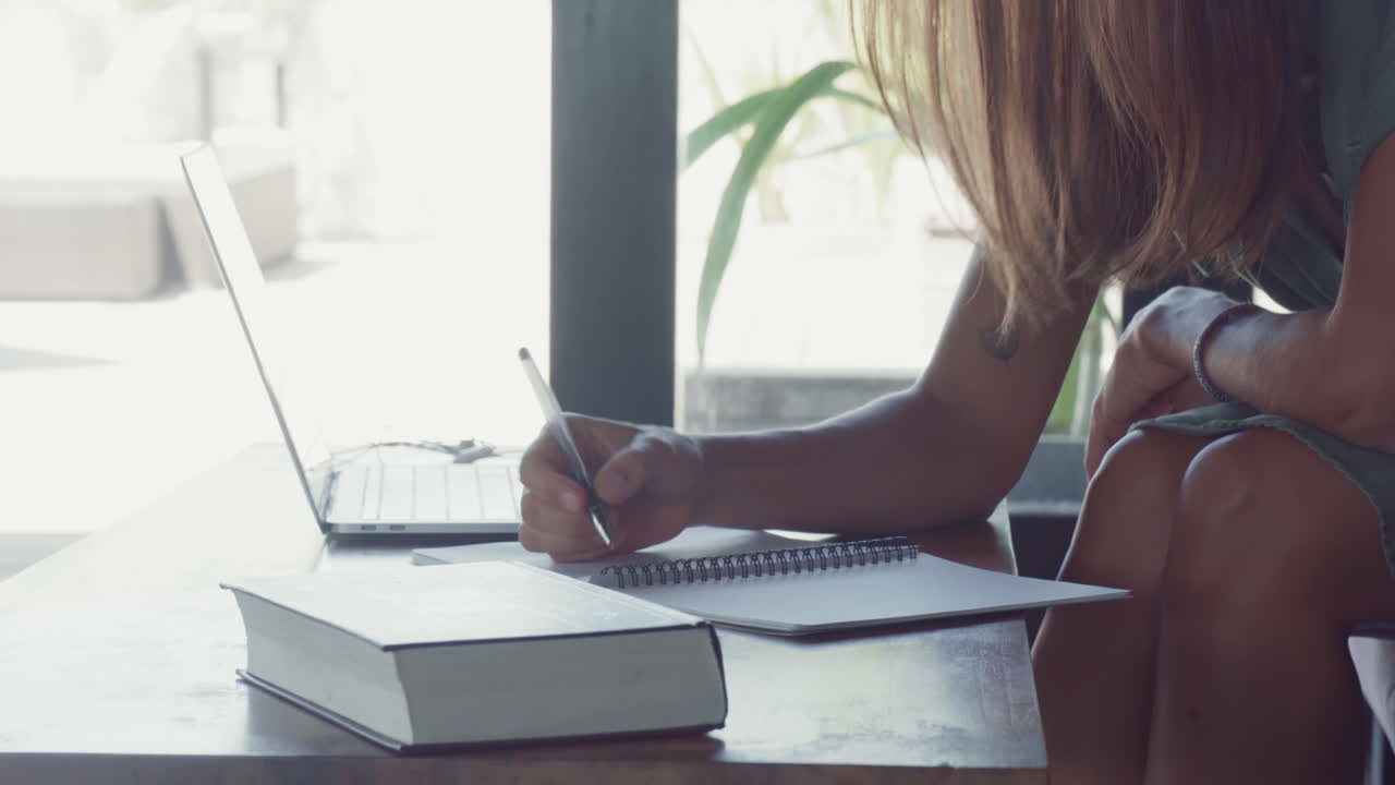 Long-haired Person Writing in Notebook