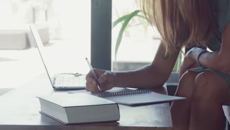 long-haired person writing in notebook
