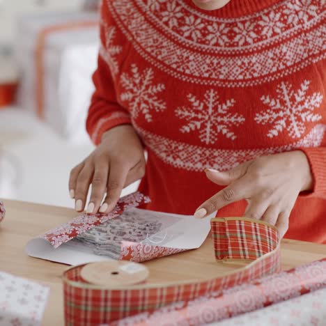 mujer joven envolviendo cuidadosamente un regalo de navidad