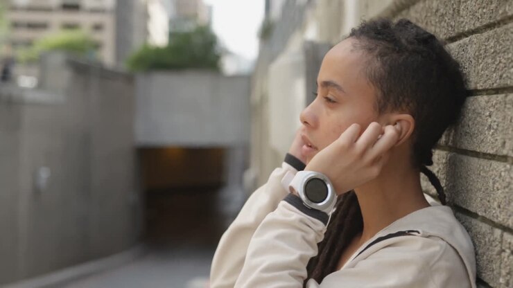 Vista laterale di una giovane donna afroamericana che indossa auricolari in città 4k