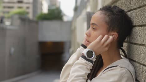 Side-view-of-young-African-American-woman-wearing-earphones-in-the-city-4k