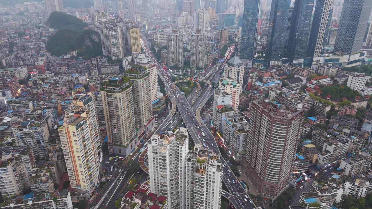 Aerial of a massive, multi-tiered traffic interchange and highway flyover cutting through the dense cityscape of Guiyang, Guizhou Province. Urban logistics and density. China, UHD