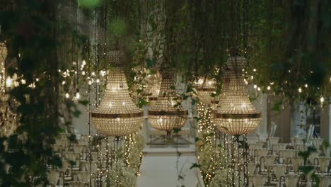 luxury chandeliers glow over floral aisle with chairs set for ceremony