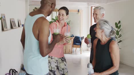 Glückliche,-Vielfältige-Senioren,-Die-Mit-Einer-Pilates-Trainerin-Sprechen-Und-Trinken,-Unverändert,-In-Zeitlupe