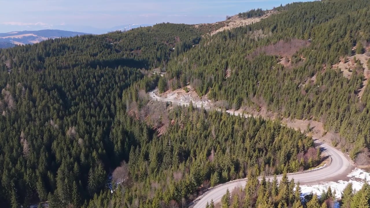 Bacino di Liptov, Slovacchia, tortuosa strada di montagna attraverso pineta e colline sotto i Tatra Occidentali vicino a Liptovský Mikuláš all'inizio della primavera, paesaggio panoramico ripreso da drone
