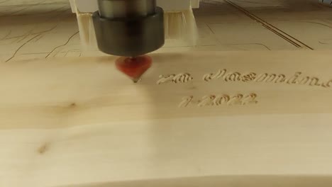 máquina de enrutador cnc tallando un texto en un tablón de madera