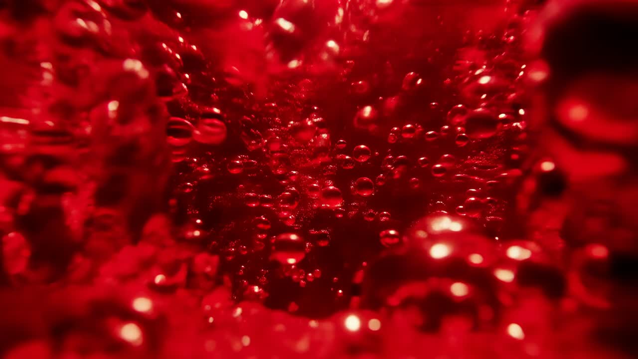 Rifocalizzazione con obiettivo macro, che mostra bolle di gas sferiche in aumento che si uniscono in una camera rossa, alla ricerca della superficie