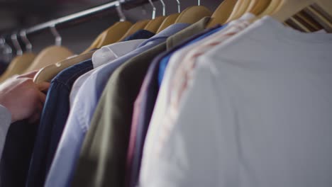 close up of man at home choosing business suit from clothes rail for job interview 2