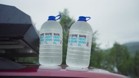 two large bottles of water placed on top of a car in sifjord, norway - close up