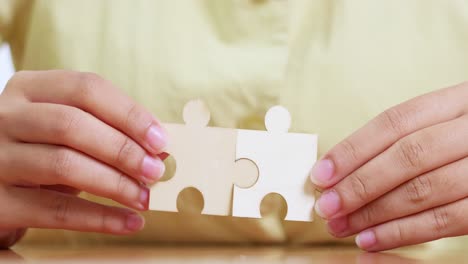 two hands connect puzzle pieces symbolizing teamwork and collaboration in a home office setting