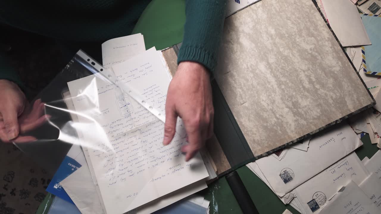 Home archivist organising personal mail letters into A4 plastic sleeve