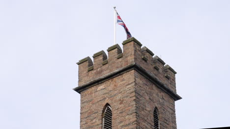 a british castle tower displays a union flag also known as a union jack