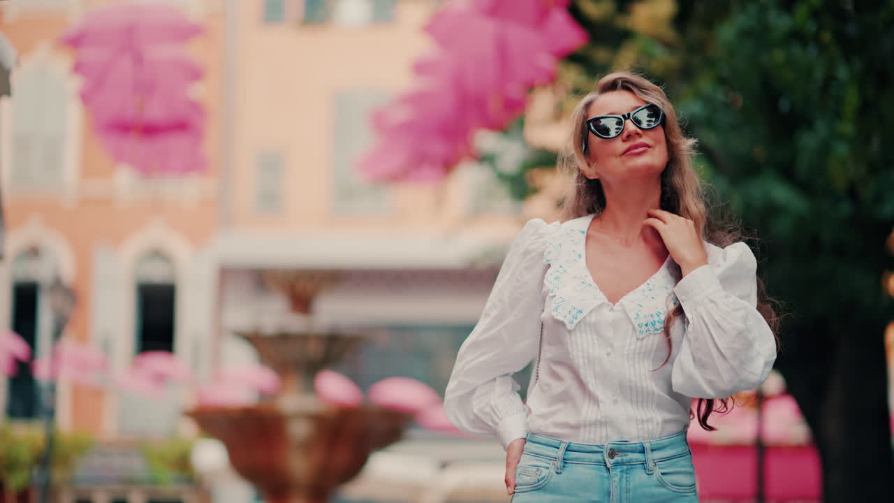 Woman walking under rows of pink umbrellas above the streets of the old town of Grasse, France