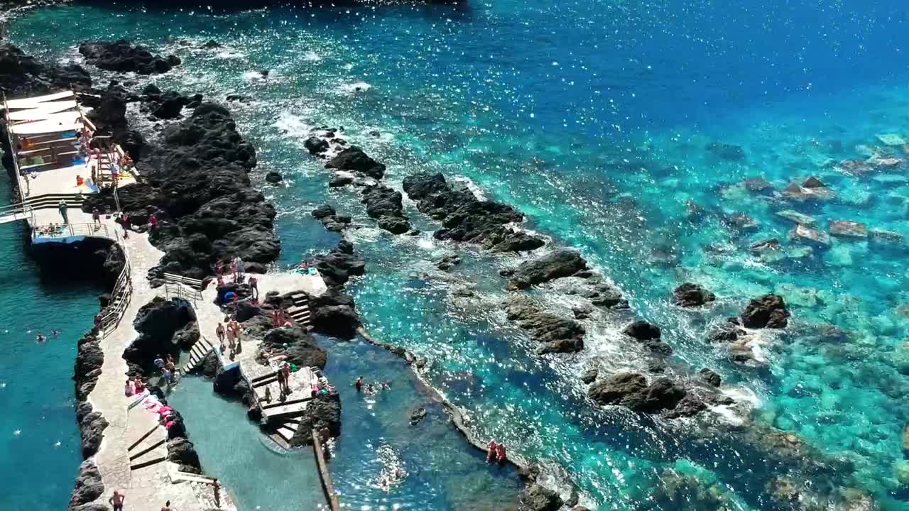 Aerial drone footage of the natural pools of Garachico Caletón. Blue ocean and the natural pools functioning as playas at Tenerife. Nice waves hit the rocks in the water.