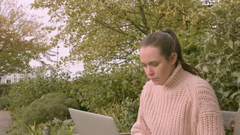 Mujer-Trabajando-En-Una-Computadora-Portátil-En-Un-Parque-Asintiendo-Con-La-Cabeza-Sintiéndose-Realizada