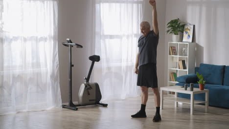 morning gymnastics of middle-aged man caring about health training alone in living room keeping good physical condition at elderly age