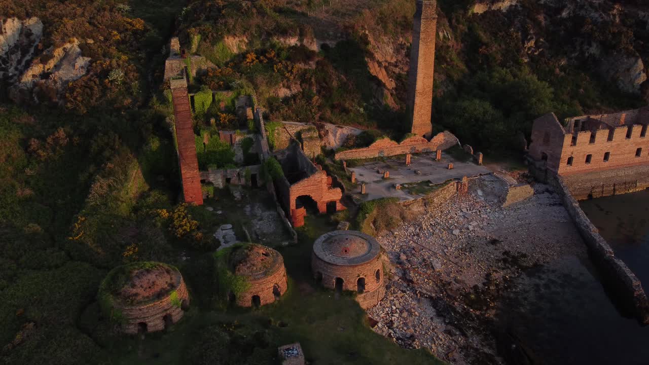 포트 웬 버려진 해안 버려진 벽돌 공장은 황금빛 일출 시골 만 공중 조감도 느린 궤도 오른쪽으로 남아 있습니다.