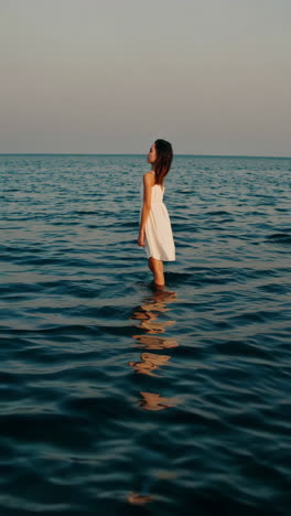 serene woman in white dress by the ocean at sunset