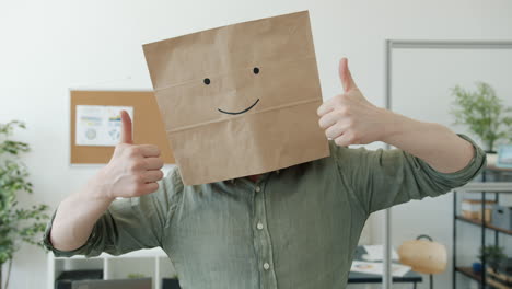 person with a paper bag on head giving thumbs up