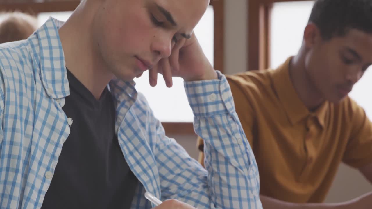 Ragazzo caucasico che scrive in una classe di scuola superiore.