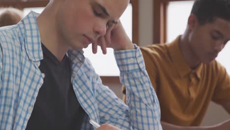 niño caucásico escribiendo en la clase de secundaria